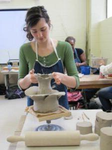 Ceramics student moulding clay on a turntable.